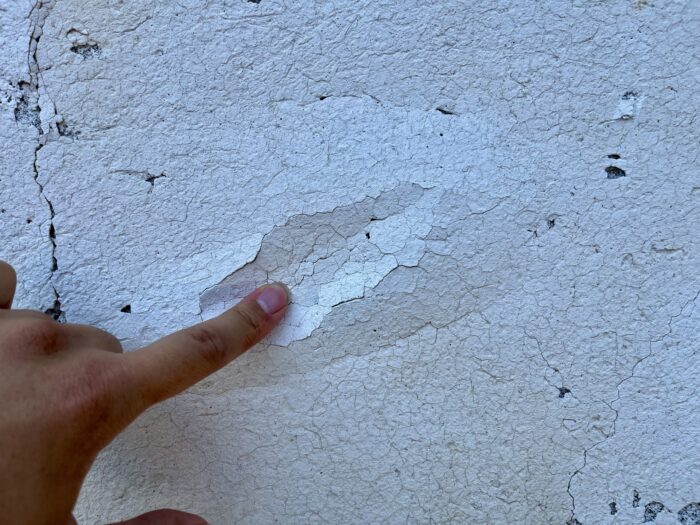外壁のひび割れと塗装の劣化を確認している様子