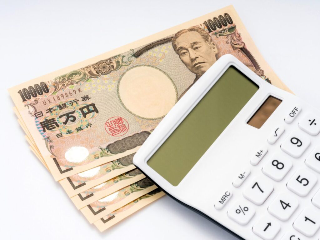 一万円札と電卓で修繕工事の費用を確認するイメージ