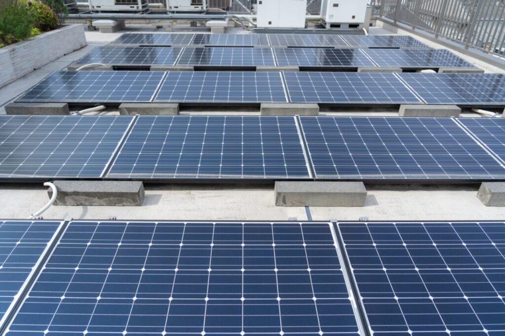 建物の屋上に複数の太陽光パネルが設置されている様子