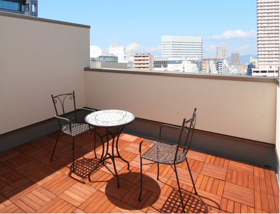 木製デッキにテーブルと椅子を配置した、街並みを望む屋上テラス